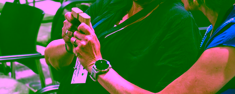 Two people in a lecture hall are holding a wooden artefact together, part of a creative design session at the COINTEND symposium.